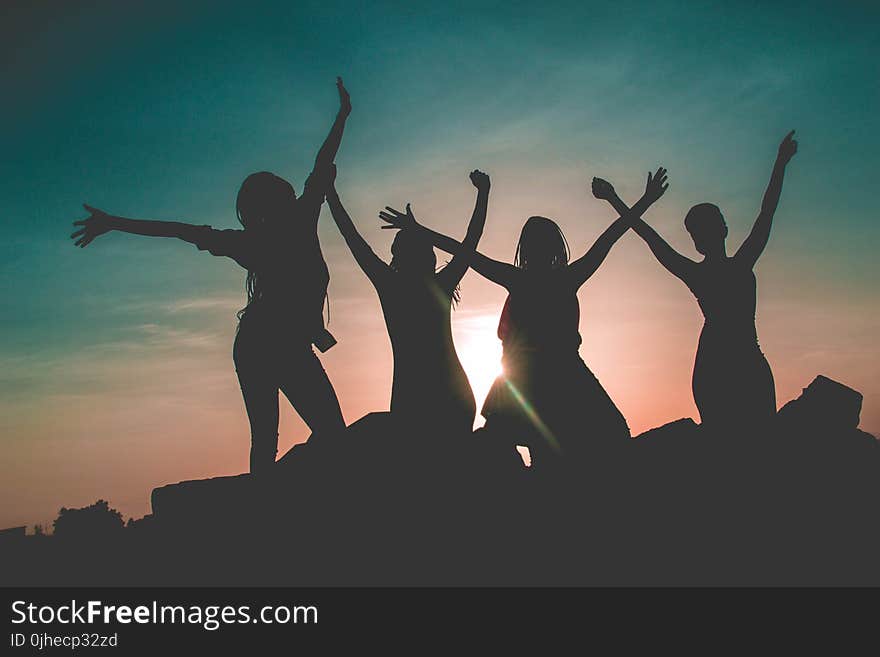 Silhouette of Four People Against Sun Background