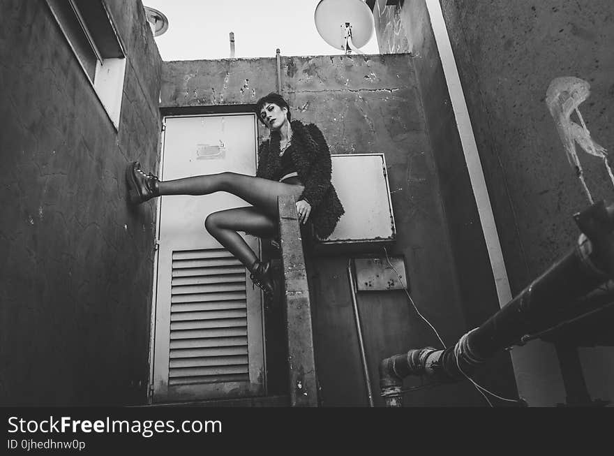 Woman in Fur Coat Sitting on Concrete Handrail