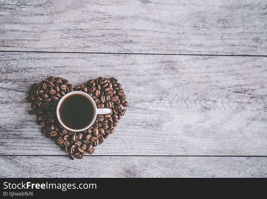 White Ceramic Mug Filled With Brown Liquid on Heart-shaped Coffee Beans