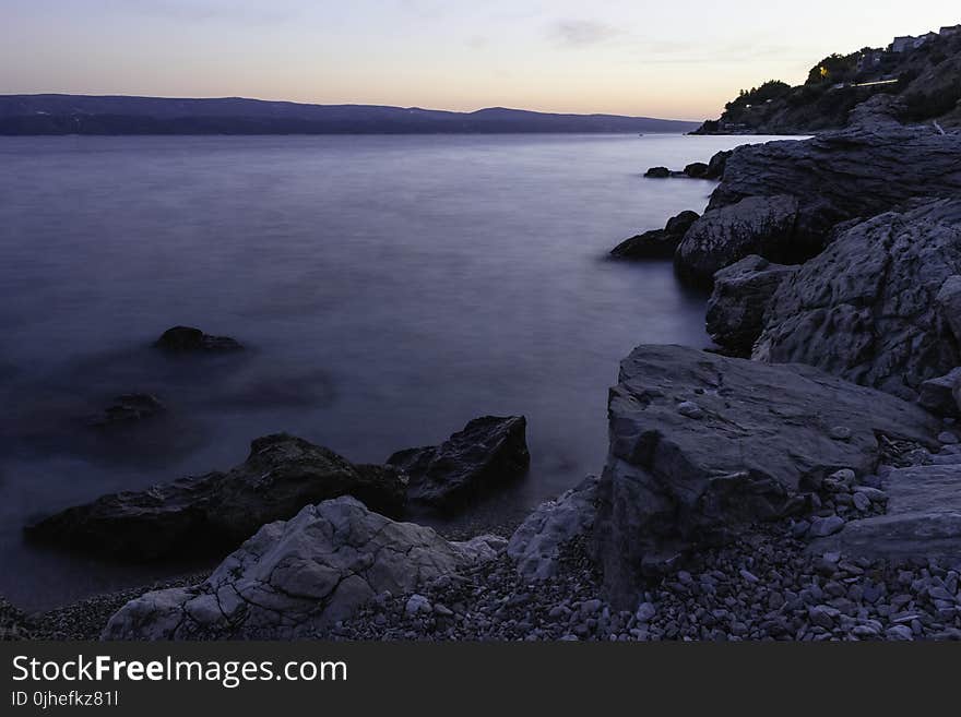 Photo of Calm Body of Water Beside Rock Formations