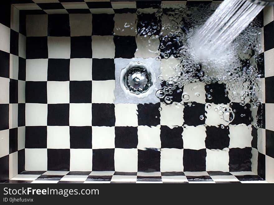 Water Flowing on White and Black Checked Bath Tub