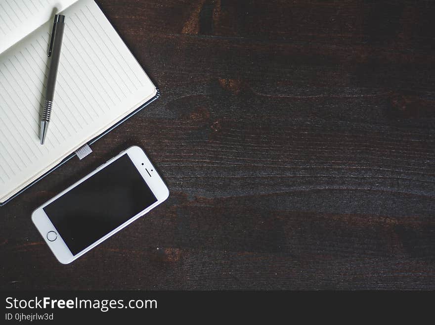 Silver Iphone 6 Beside White Book With Pen