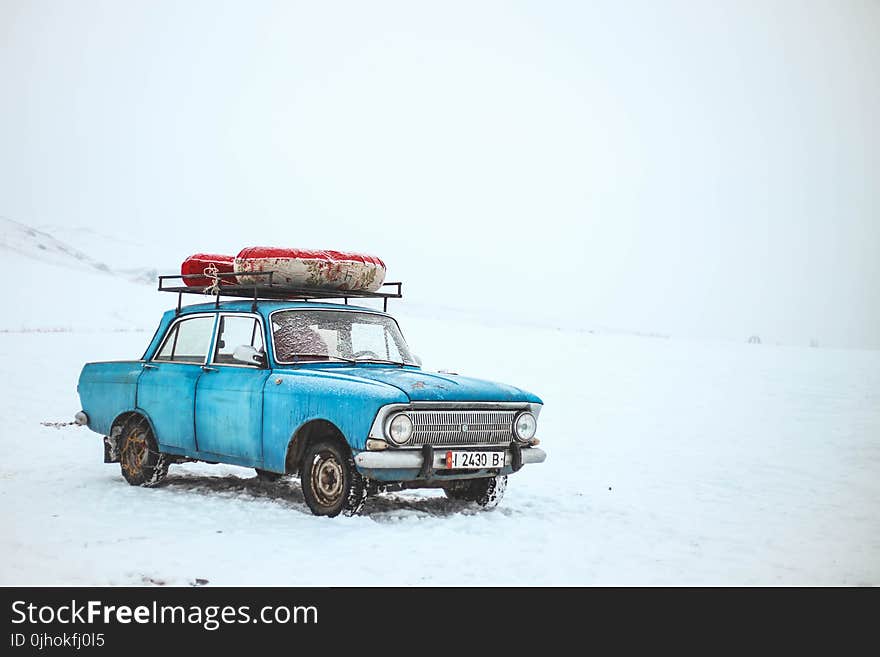 Blue Sedan on Snow at Daytime