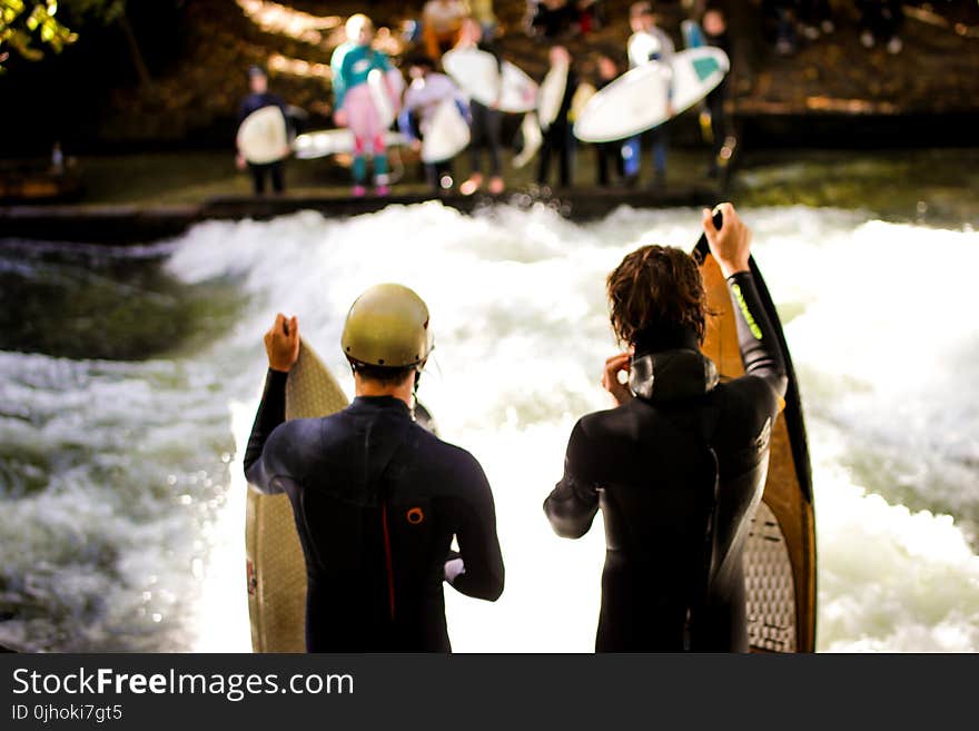 Two Men Wearing Black Wet Suits Holding Brown Wooden Surfboards