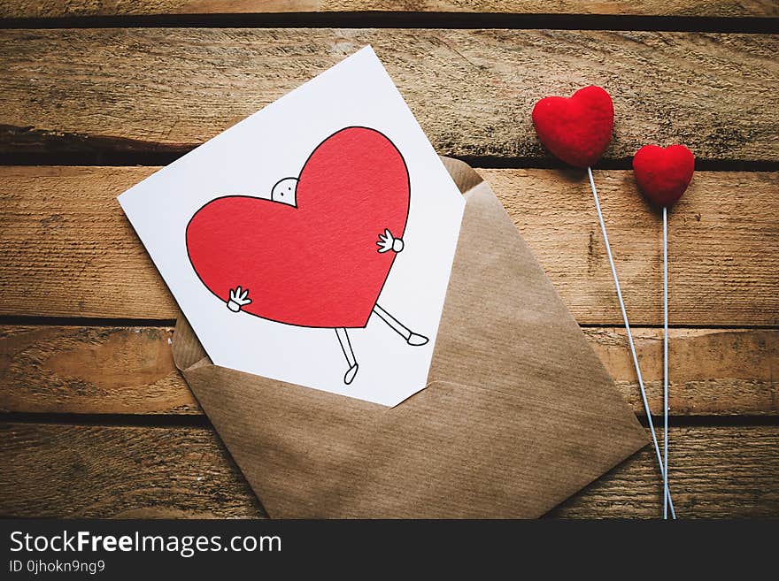 White, Black, and Red Person Carrying Heart Illustration in Brown Envelope