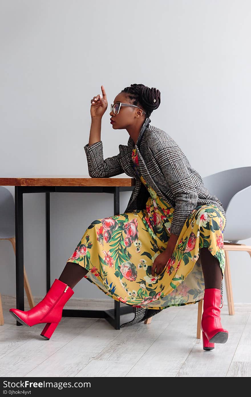 Woman Sitting on a Chair With Open Legs and Right Hand on Top of Wooden Table