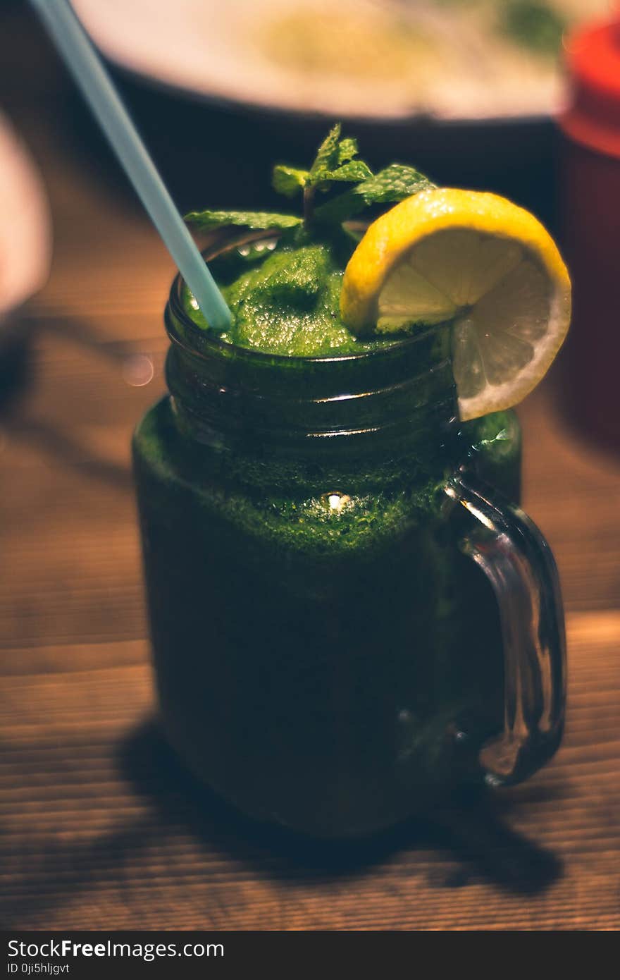 Close-up Photography of Clear Glass Mason Jar Mug With Green Juice and Sliced Citrus Toppings