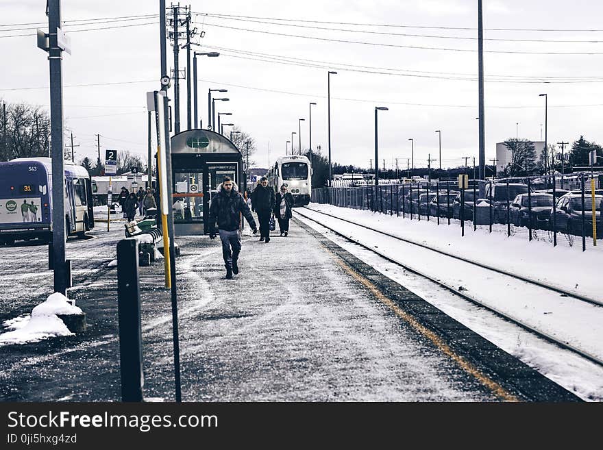 Man Wearing Jacket and Jeans Walking on Road