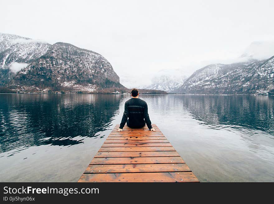 Man Seating in the Rail Way Near Body of Water