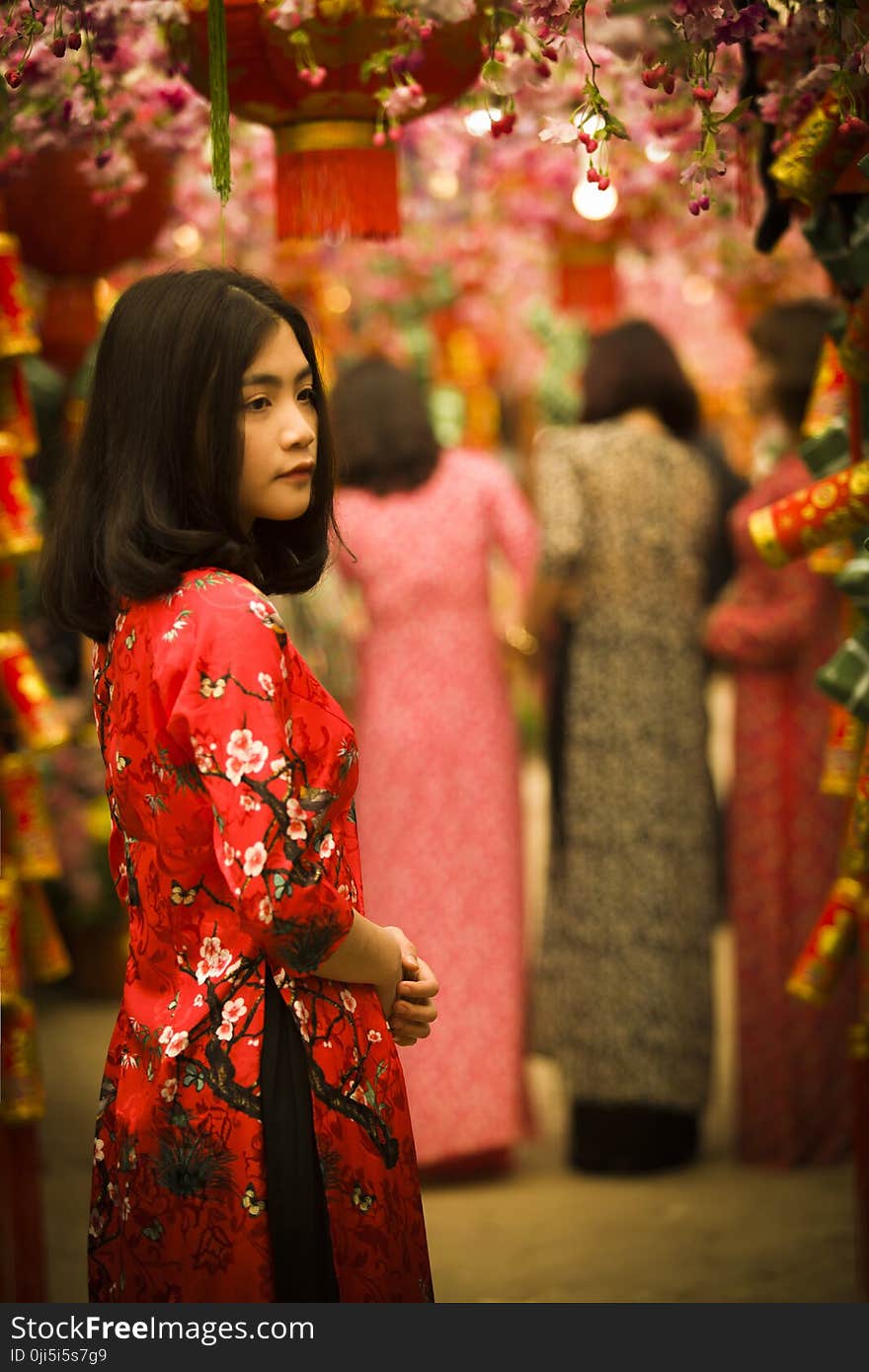 Woman in Red and White Floral Slit Dress Standing in Red Floral Arch