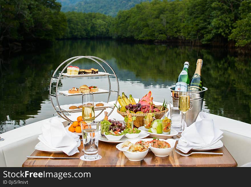 Food Photography of Food and Wine Bottles on Table Inside Boat