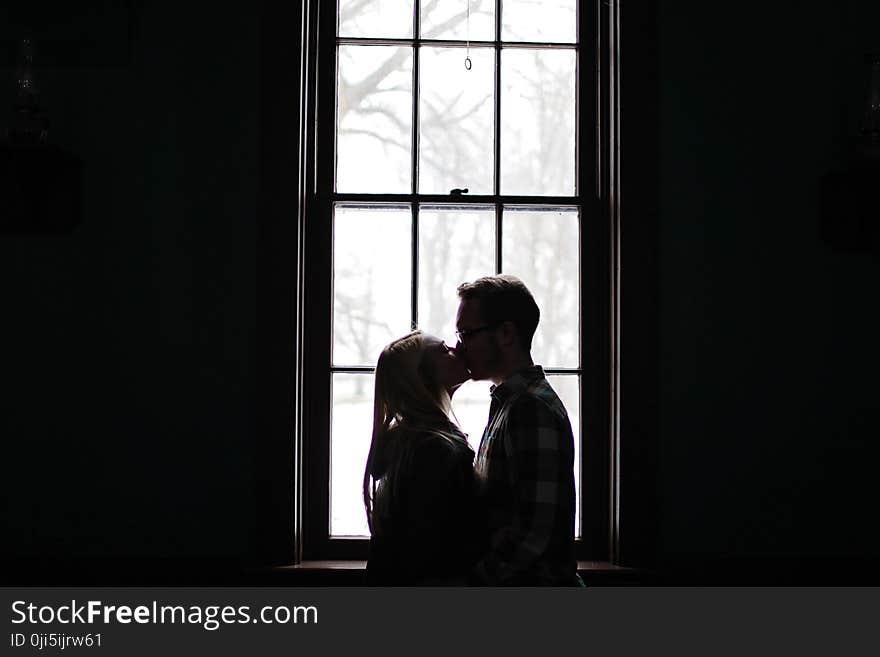 Man and Woman Kissing Beside Window