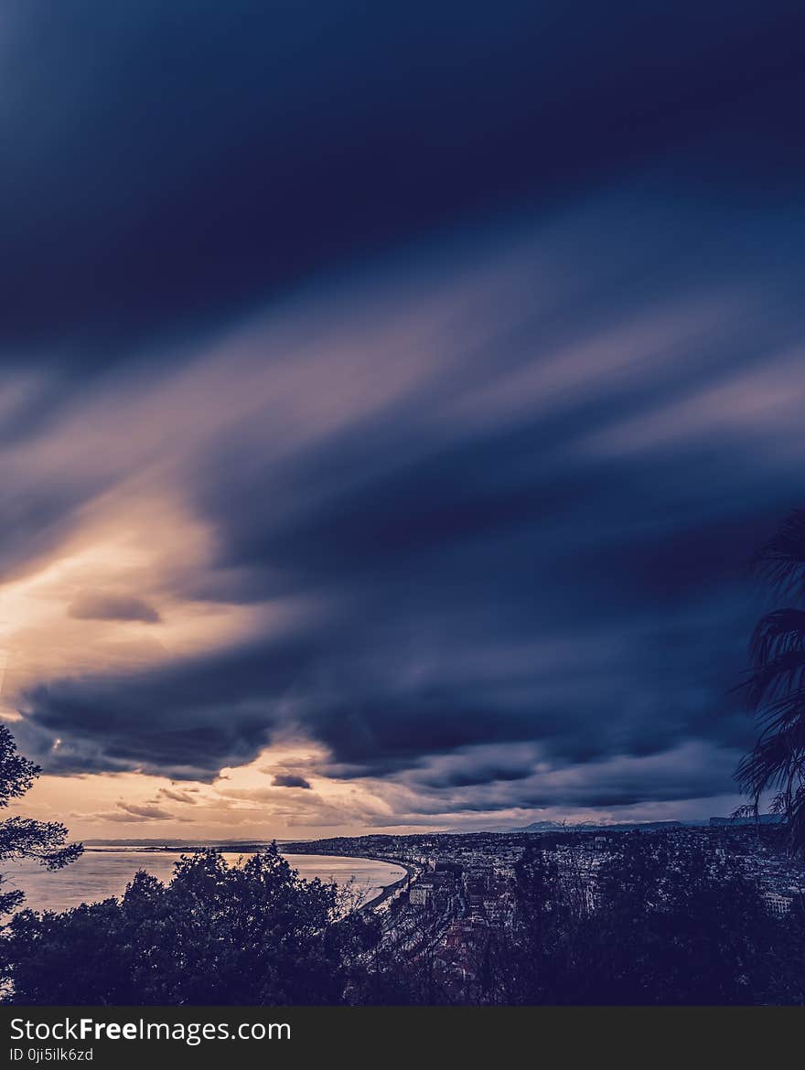 City Beside Sea Under Cloudy Sky