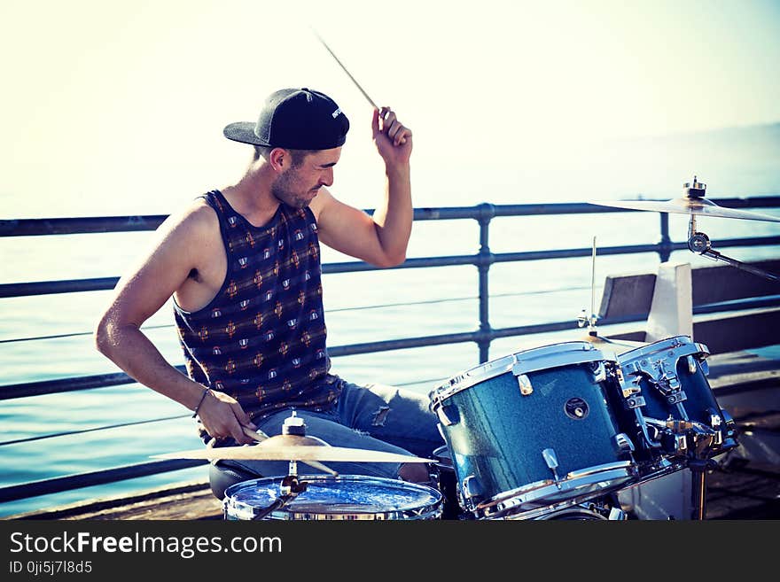 Man Playing Drum Near Bay at Day Time