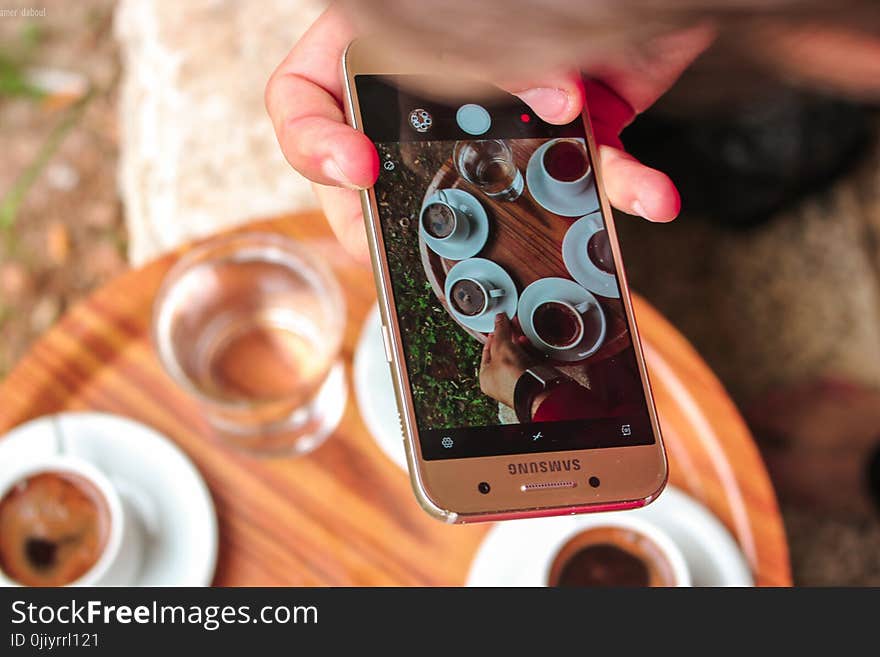 Person Holding a Samsung Galaxy Smartphone Taking a Picture on Their Coffees