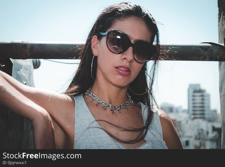 Woman Wearing Sunglasses While Leaning on Wall