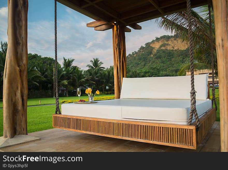 Brown Wooden Framed With White Mattress Hanging Bed Surrounded by Green Grass