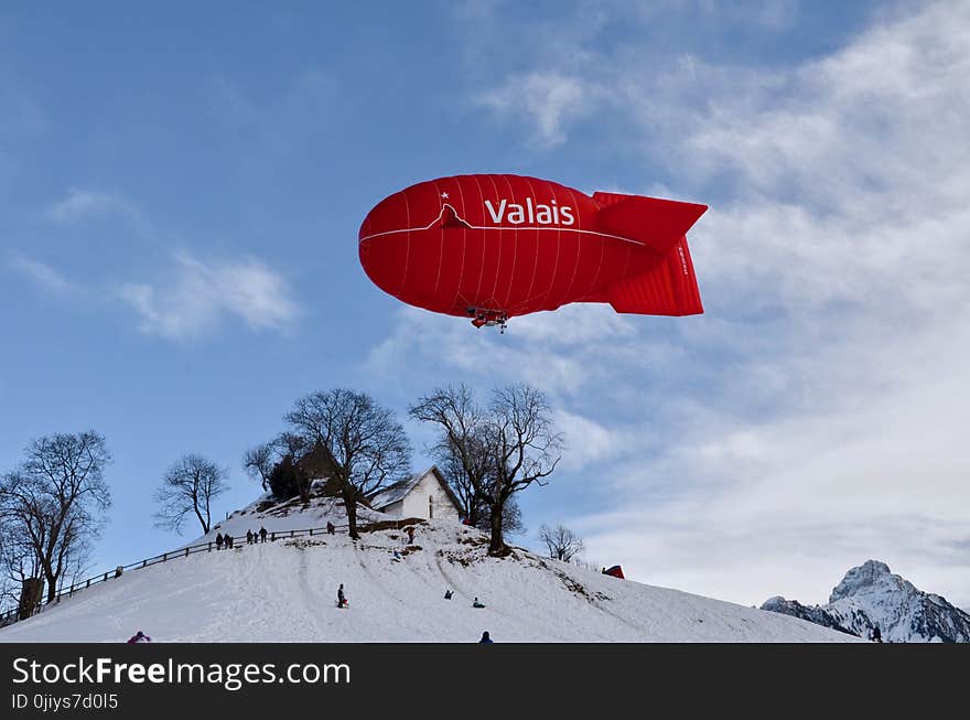 Red Valais Blimp Above White Wooden House