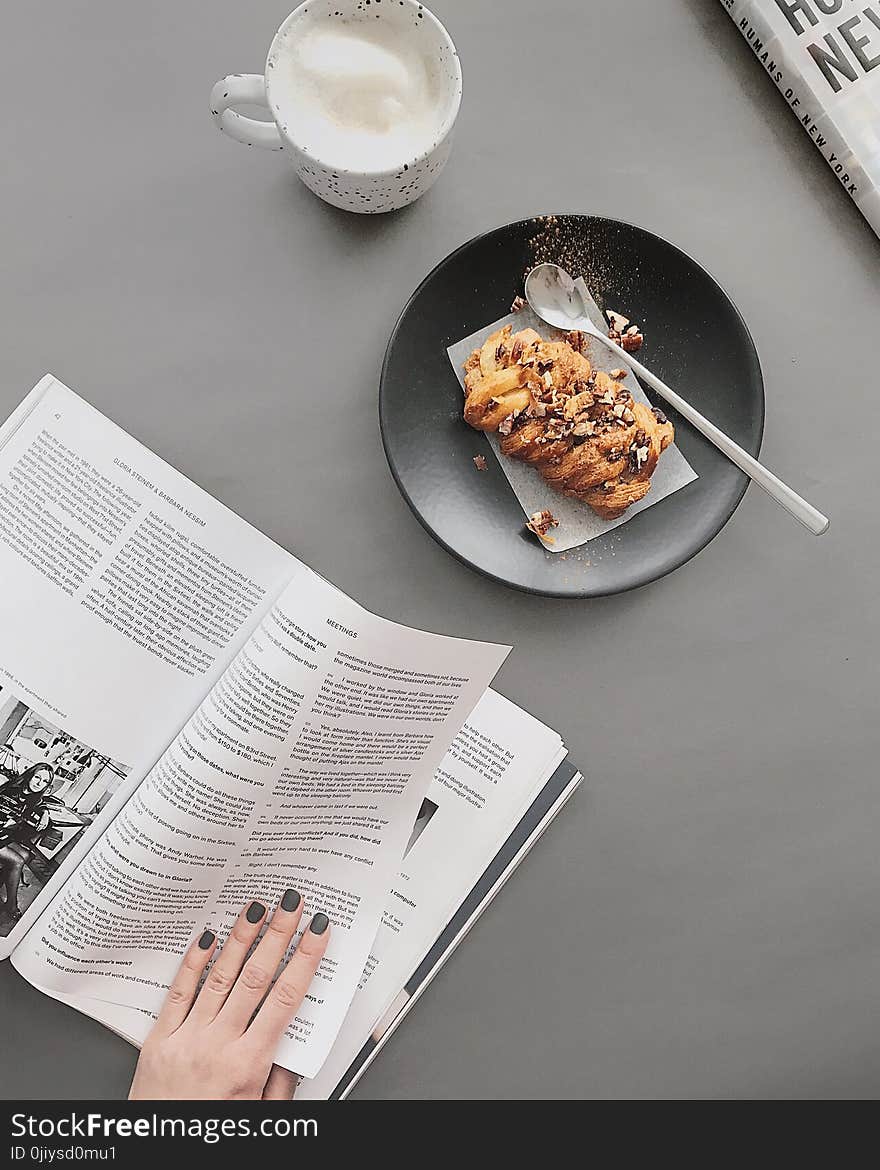 Bread on Round Black Plate Near White Ceramic Cup