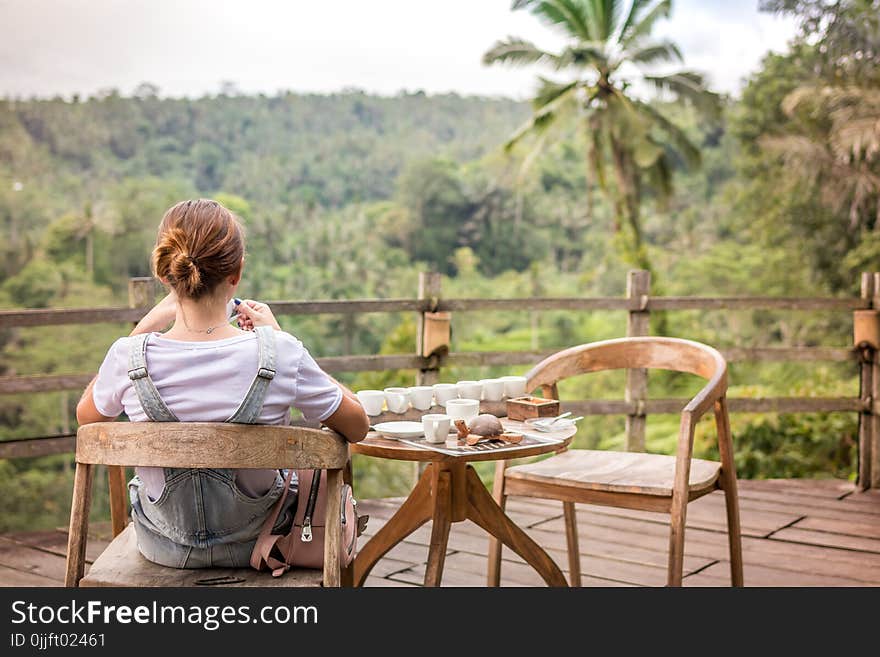 Brown-haired Woman Sitting on Brown Wooden Chair on Patio