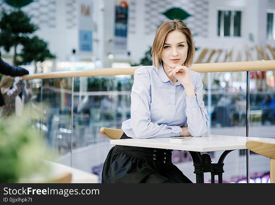 A Young Woman Talking Through The Phone. The Girl Is Sitting At The Table And Makes An Order. Business Woman