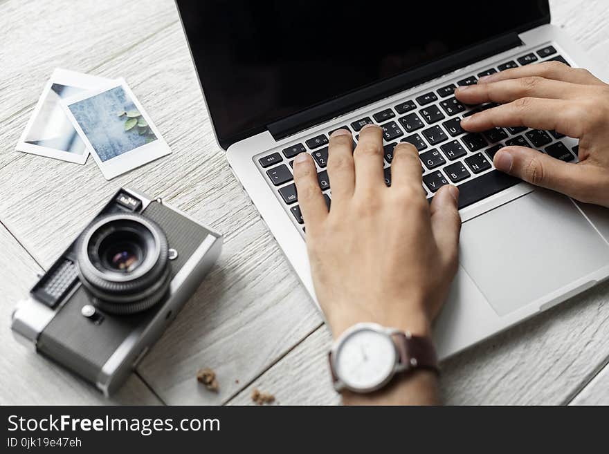 Person Using Macbook Pro Beside Grey Camera on Table