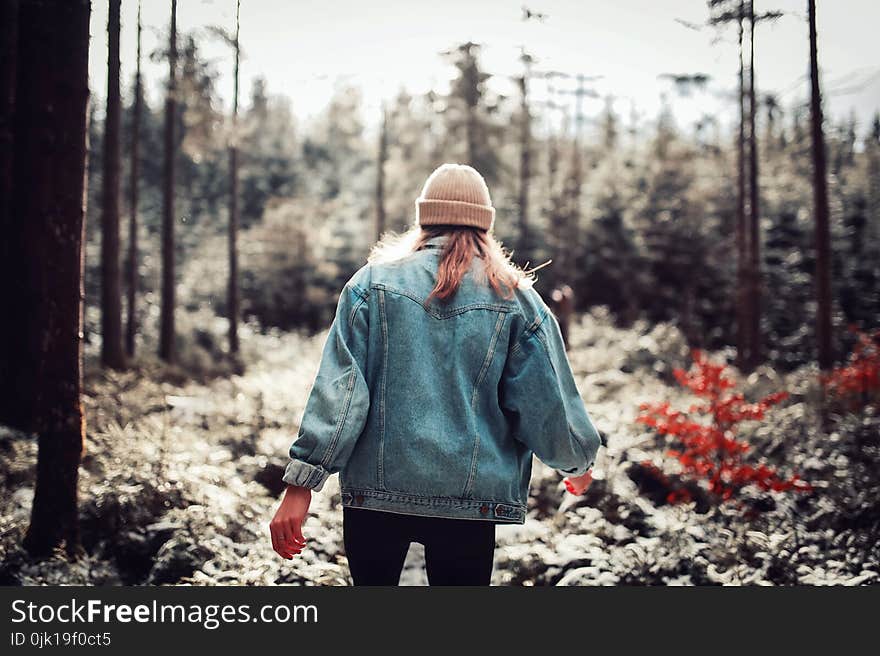 Woman Wearing Blue Denim Jacket and White Beanie Walking in the Forest