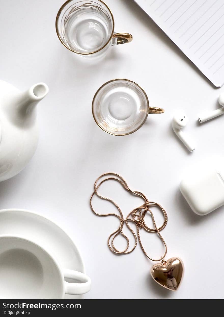 Gold-colored Heart Pendant Necklace Beside Two Glass Mugs on Table