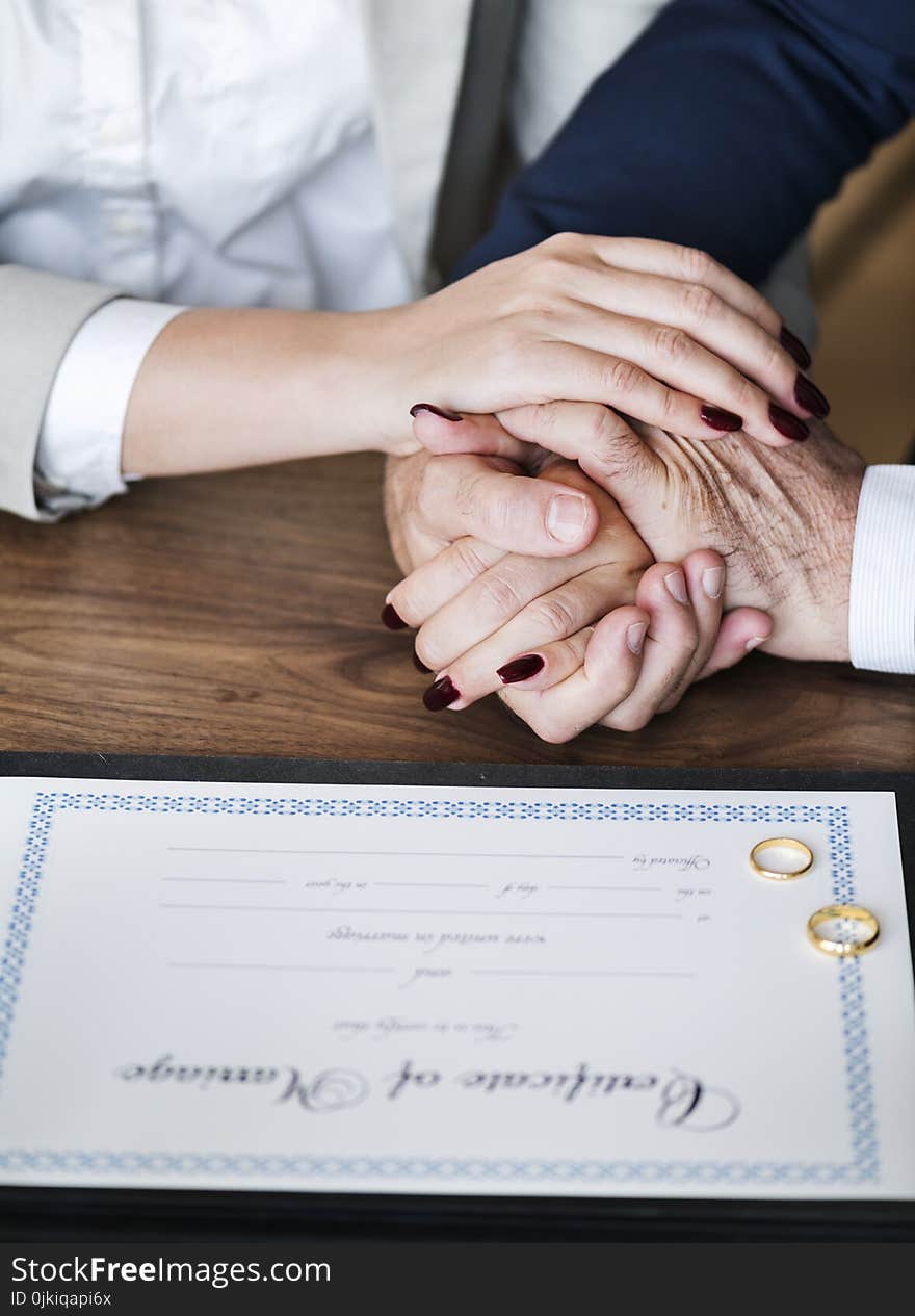 Man and Woman Holding Hands on Brown Wooden Table