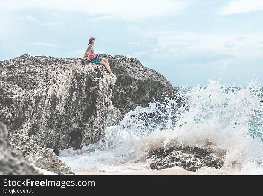 Woman Sitting of Rock Near Body of Water