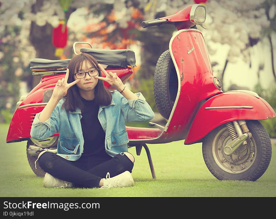 Girl Doing Peace Sign Indian Sitting in Front of Red Scooter Motorcycle