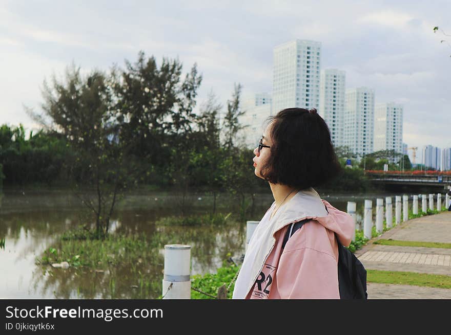 Woman Wearing Pink Hoodie Stand in Front of Body of Water