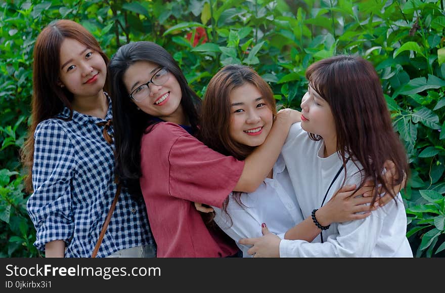 Four Women Wearing Shirts Standing Beside Green Leaf Plants