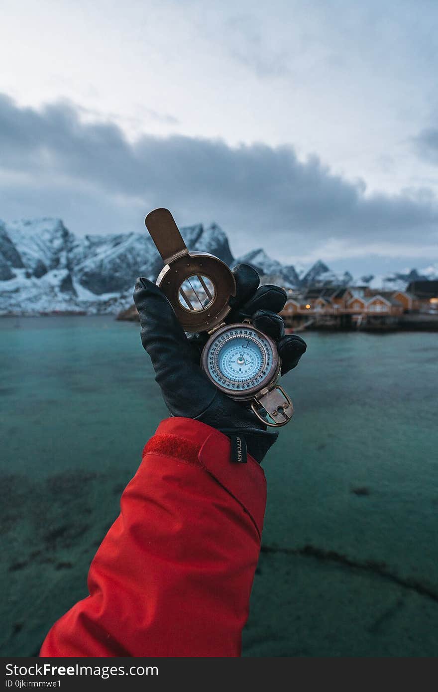 Person Wearing Black Leather Gloves Holding Brass-colored Compass