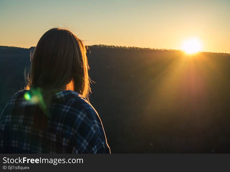 Woman Wearing Plaid Shirt Facing Sun during Golden Hour