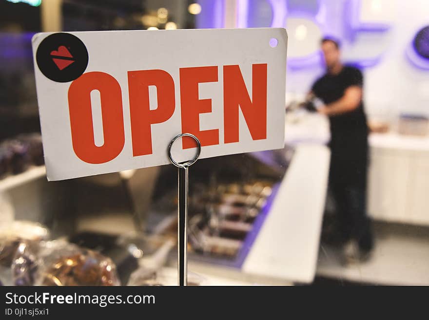 Shallow Focus Photography of Red and White Open Signage Near Man Wearing Black Shirt