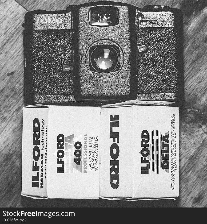 Black Lomo Compact Camera Beside Ilford Delta 400 Black & White Film Box