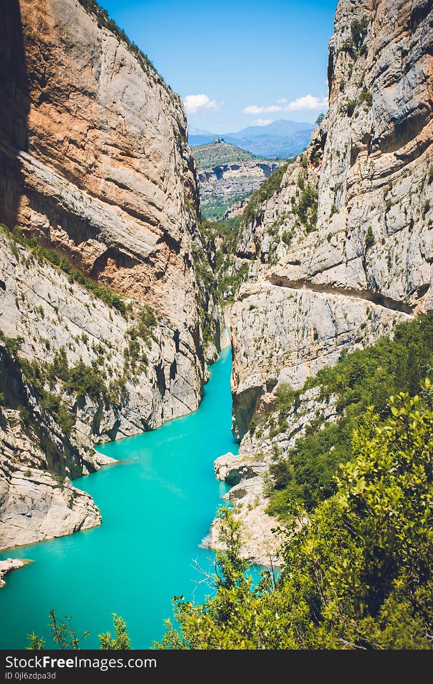 Body of Water Surrounded by Mountain Under Blue Sky at Daytime