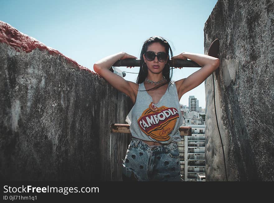 Woman Wearing Blue Tank Top Beside Concrete Walls