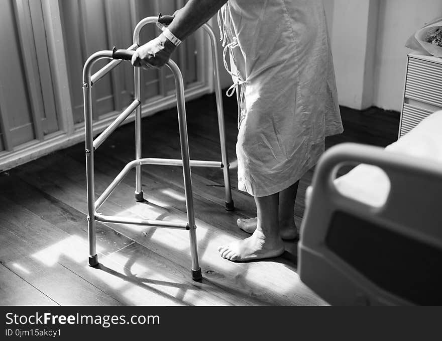 Person Holding Medical Walker Beside White Hospital Bed