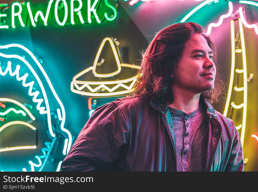 Man Standing in Front of Neon Signages