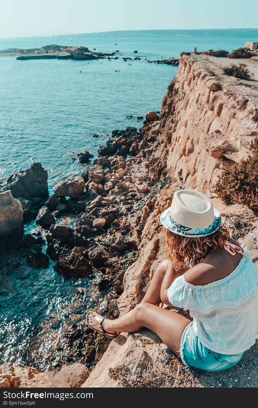 Woman Sitting in Stone Near Body of Water