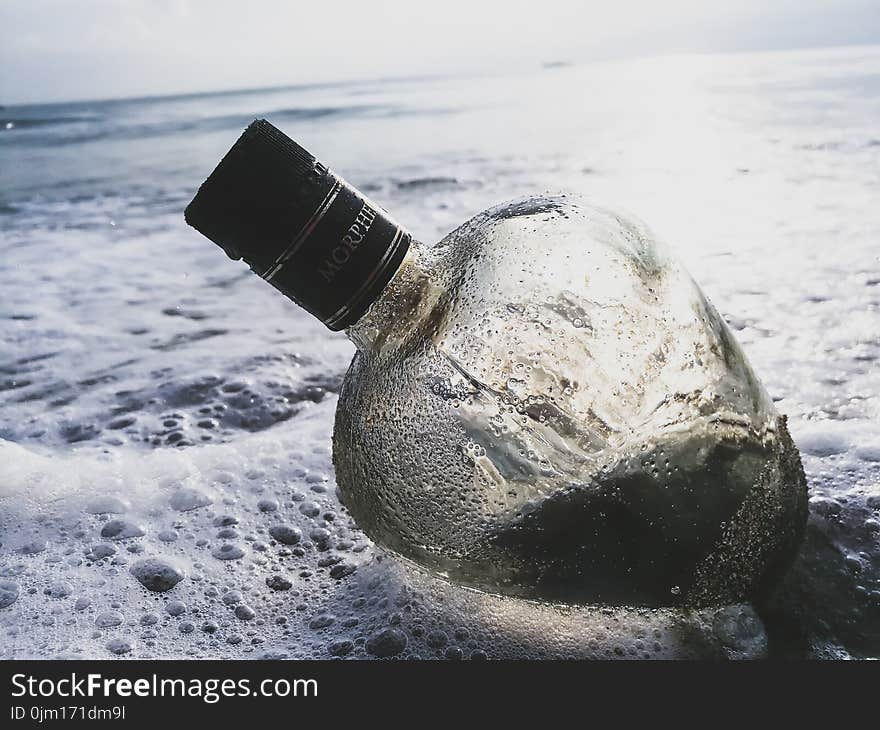 Clear Glass Bottle on Body of Water