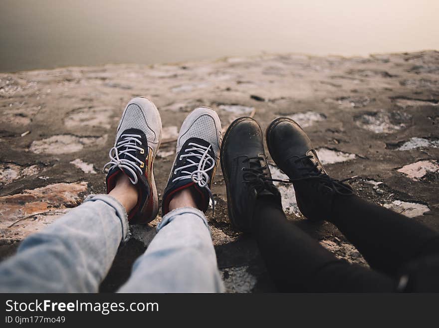 Two Person Wearing Pants and Shoes Sits on Ground at Daytime