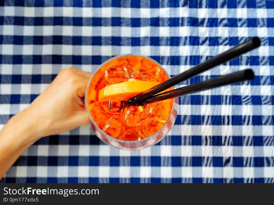 Person Holding Clear Drinking Glass With Two Black Straws