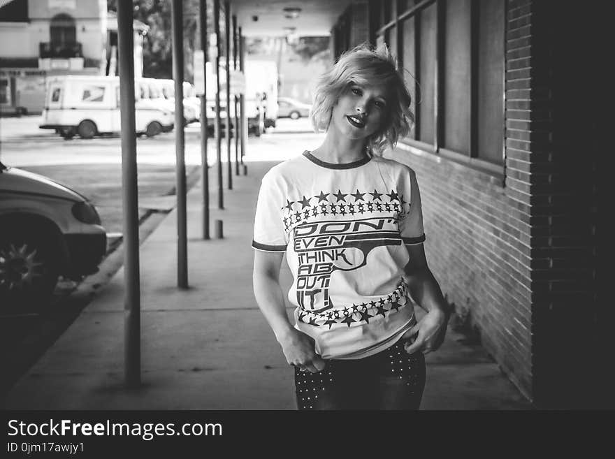 Woman in Crew-neck Shirt Standing Beside Brick Wall Building