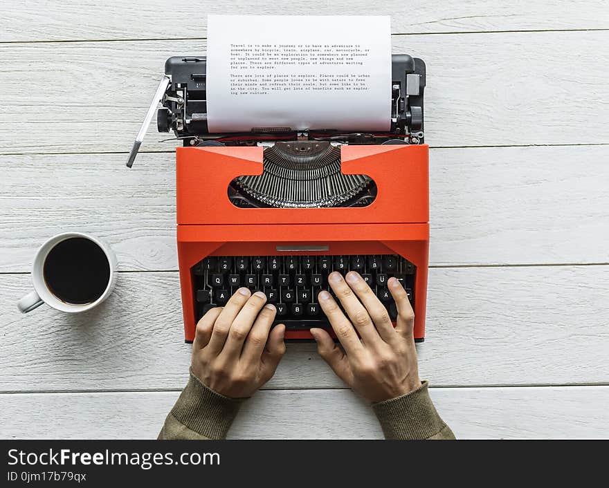 Person Holding Black and Orange Typewriter