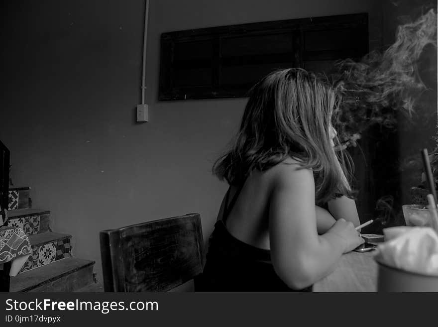 Grayscale Photo of Woman Sitting on Chair Near Chair