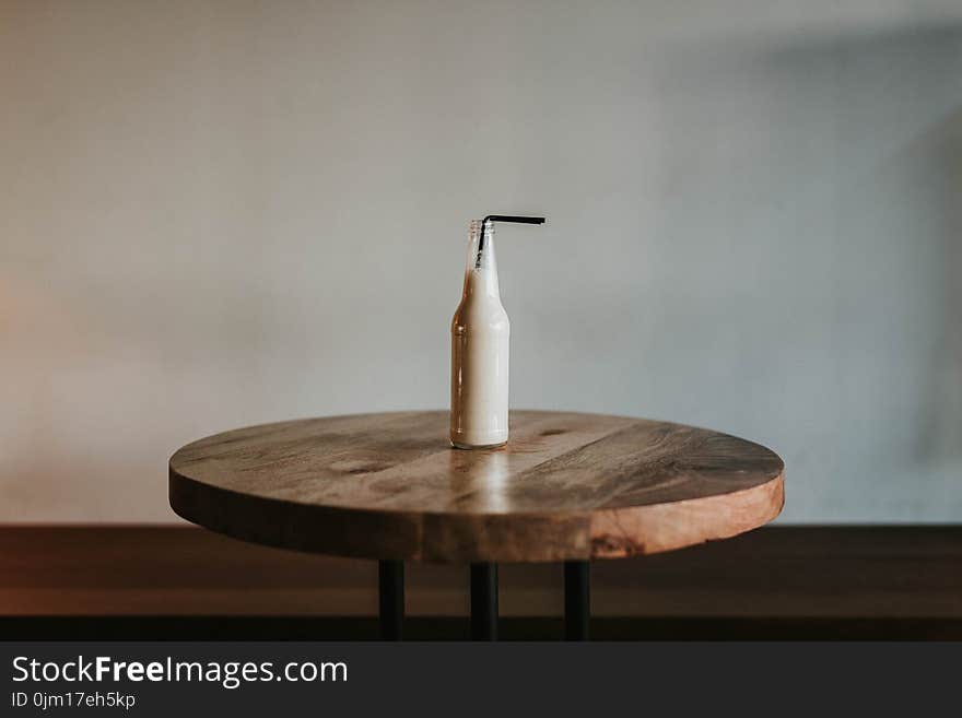 Glass Bottle Filled With Black Straw on Brown Wooden Table