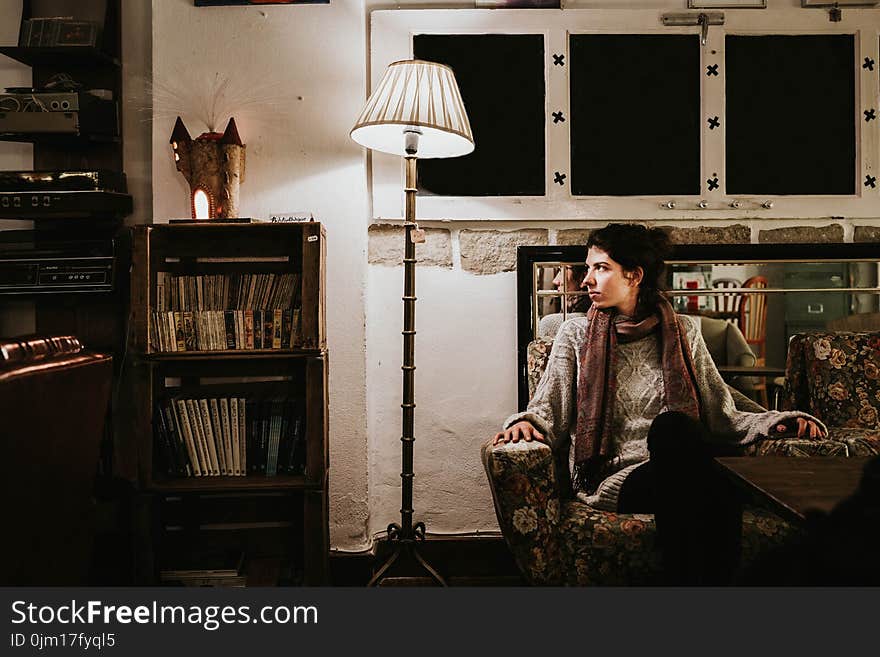 Woman Sitting on Sofa Chair Beside Floor Lamp Leaning on Side